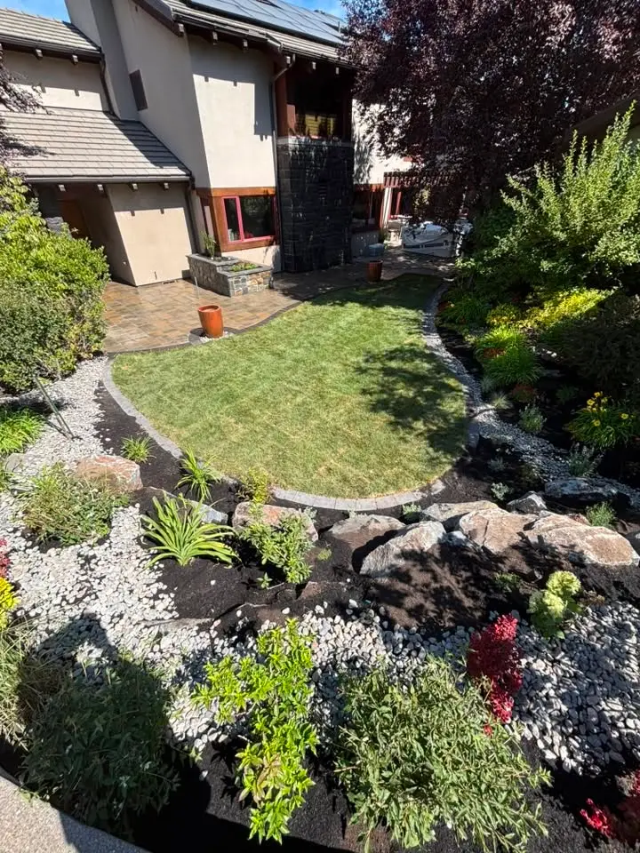 New lawn, river rock, and planting beds in front of a stucco home