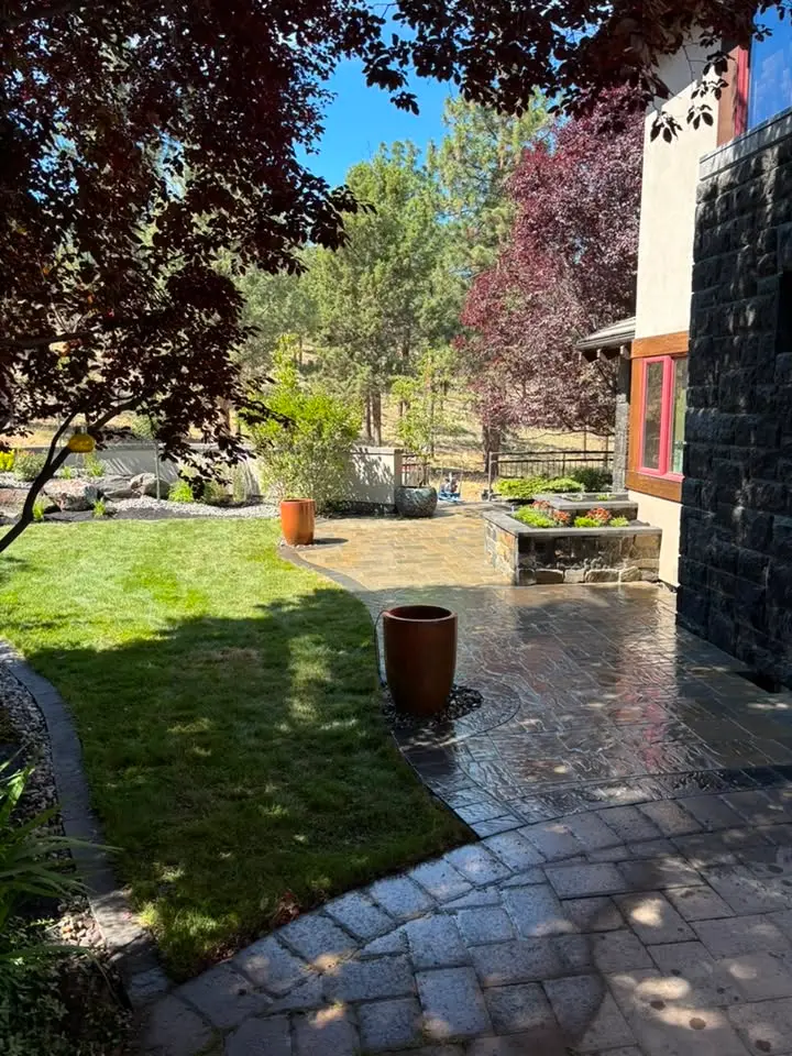 Stamped concrete patio curving around a lawn with planters